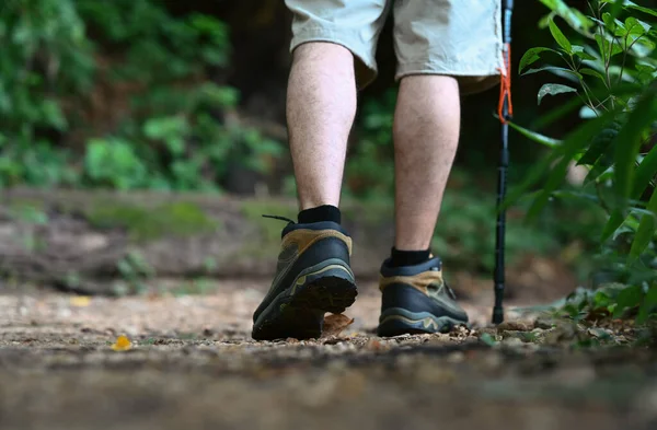 Low angle view, man traveller legs with hiking boot trekking along trail in forest.