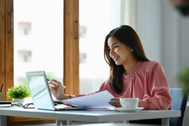 Harika bir milenyum kadın sekreteri iş yerinde oturuyor ve dizüstü bilgisayarla çalışıyor..