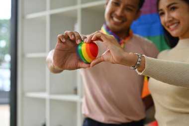 Erkek ve bayan arkadaşlar gülen yüzlü gökkuşağı kalbi gösteriyorlar. LGBTQ, arkadaşlık ve yaşam tarzı konsepti.