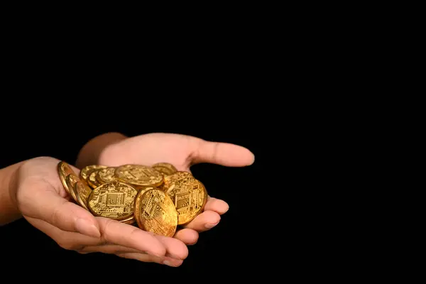 Unrecognizable woman hands with gold coins isolated on a dark background. Finance, investment and save money concept.