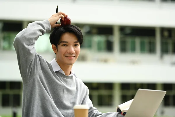 Smiling asian male student learning and study online on laptop in campus garden. Education, Learning and lifestyle.
