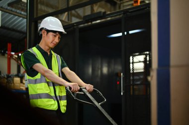 Güvenlik kasketi takmış bir erkek işçiyi palet kamyonu çekerken çekmişler. Sıralar dolusu depoda ellerinde mallarla yürüyorlarmış..