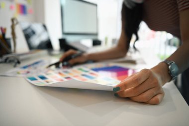 Kulaklıklı, genç, şık bir kadın grafik stüdyosunda yeni tasarım projesi üzerinde çalışıyor..