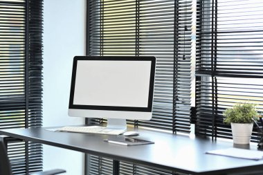 Siyah ofis masasında klavyesi, günlüğü ve saksısı olan boş ekran bilgisayarı.