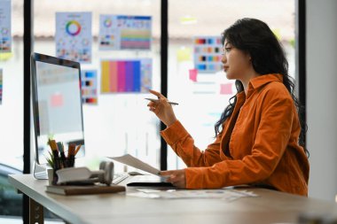 Çekici kadın serbest çalışan bilgisayar ekranına bakıyor, yaratıcı iş yerinde yeni bir proje üzerinde çalışıyor..