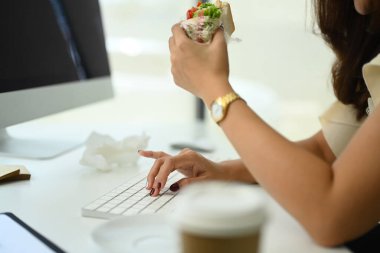 Kadın ofis çalışanının öğle yemeğinde masada oturup sandviç yediği görüntüler..