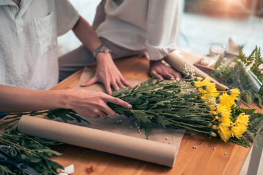 Erkek çiçekçi çiçekçide saklanmış çiçekçinin ahşap masasında çiçek paketliyor. Küçük işletme kavramı.