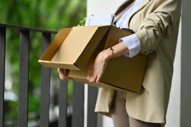 İşten ayrıldıktan sonra elinde eşyalarla dolu karton bir kutu tutan kadın. İş kaybı, işsiz kavramı.