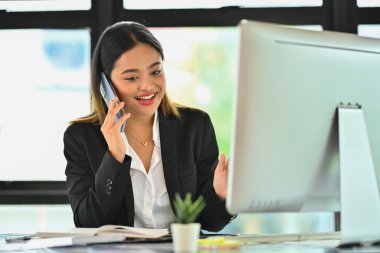 Güzel bir kadın yatırım danışmanı hoş bir telefon görüşmesi yapıyor. Çalışma masasında danışmanlık yapıyor..