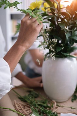 Ahşap masada çiçek düzenleyen tanınmamış bir adam. Boş zaman aktivitesi ve yaşam tarzı konsepti.