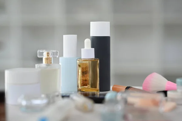Closeup view of skincare product, lotion bottle, round mirror and makeup brushes on dressing table.