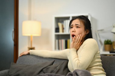 Mutsuz genç bir kadın diş ağrısı ya da diş eti iltihabı semptomlarından muzdarip yanağa dokunuyor. Diş sağlığı konsepti.