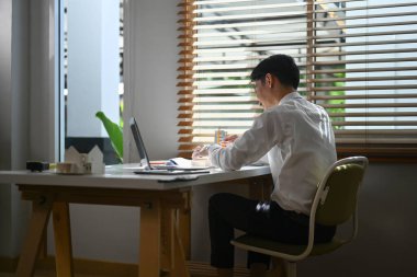 Ofiste inşaat projesinde çalışırken ev modelini inceleyen mühendisin dikiz görüntüsü.