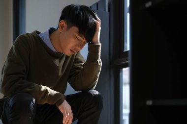 Bunalımlı adam merdivenlerde yalnız başına oturuyor, elleri başının üstünde stresli, üzgün ve endişeli. Depresyon, zihinsel sağlık konsepti.