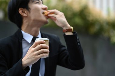 Resmi olarak Asyalı bir ofis çalışanı ofisin dışındaki merdivenlerde oturur ve öğle yemeğinde lezzetli sandviçler yer..