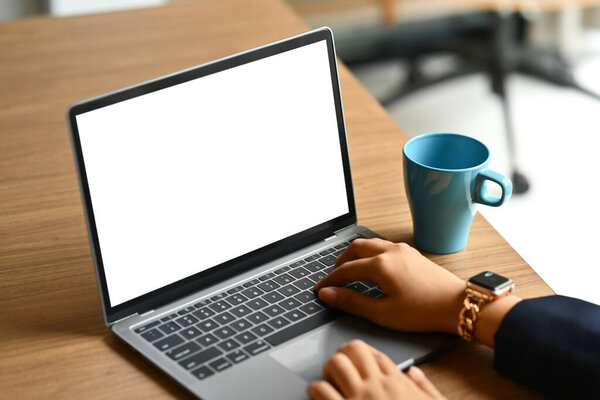 Closeup shot of Shot of unrecognizable businesswoman using a laptop on wooden office desk.