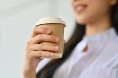 Tek kullanımlık kağıt kahve fincanı tutan iş kadını eline odaklan, teneffüste rahatla.