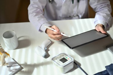 Hastanın hastalık geçmişini doldurmak için dijital tablet kullanan ya da tıp dergisine not alan doktorların genel görünümünü kapat.