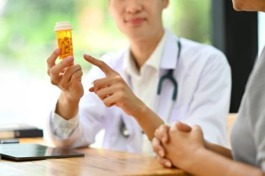 Doktor elinde ilaç şişeleriyle kıdemli hastaya ilaç tedavisini açıklıyor. Tıp ve sağlık hizmeti kavramı.