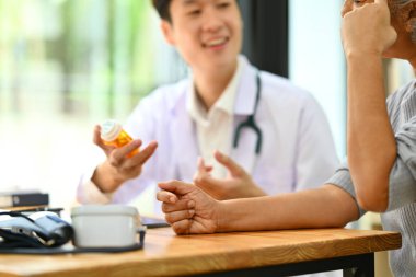 Doktor elinde ilaç şişeleriyle kıdemli hastaya ilaç tedavisini açıklıyor. Tıp ve sağlık hizmeti kavramı.