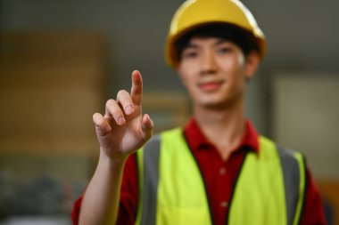 Erkek depo çalışanı sanal düğmeye basıyor ya da bir şeyi işaret ediyor. Lojistik ve imalat işgali.