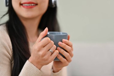 Rahat kıyafetler giyen, kanepede çay içen, hafta sonunu evde geçiren genç bir kadın..