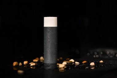 Erkekler kozmetik şişesi ile su damlası ve koyu arka planda çakıl taşları, kozmetik ambalaj şablonu tasarımı.