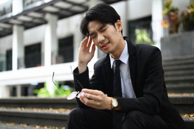 Yorgun genç iş adamı gözlüğünü çıkarıyor, yorgunluk ya da şiddetli baş ağrısı çekiyor. Sağlık sorunu kavramı.