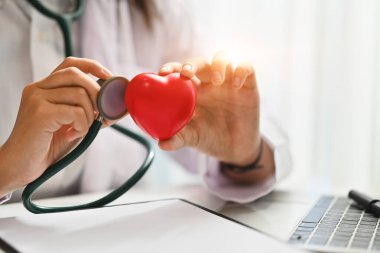 Doktor steteskop ve kırmızı kalp tutuyor. Sağlık, kardiyolojik, tıbbi ve yardım konsepti.