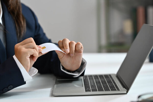 Женщина-работница уничтожает свою кредитку за столом. Концепция банкротства, финансовые проблемы.