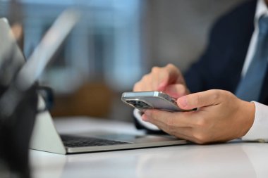 Tanınmayan iş adamı el masajı yapıyor, cep telefonundan sosyal medyayı kontrol ediyor..