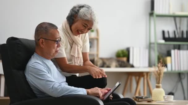 在舒适的家休息的同时 爱着使用数码平板电脑的老夫妇 老年人的生活方式和婚姻概念 — 图库视频影像