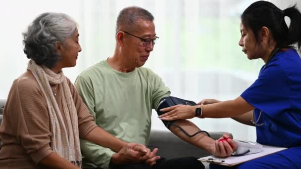 家庭訪問中に動脈血圧高齢男性を測定する女性医療従事者 高齢者医療と高血圧のコンセプト — ストック動画