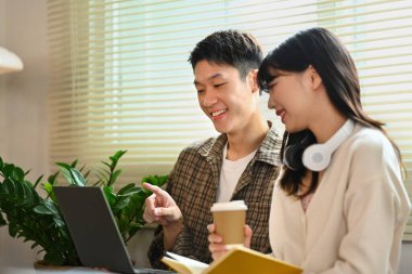 Erkek ve kız öğrenciler dizüstü bilgisayar kullanıyor ve kütüphanede akademik proje üzerinde birlikte çalışıyorlar. Eğitim ve gençlik yaşam tarzı kavramı.