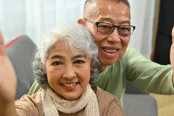 Affectionate happy old senior couple taking selfie and looking at camera.