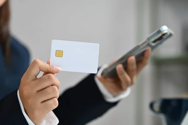 Close up businesswoman hand holding credit card and smartphone, doing online purchases or paying online.