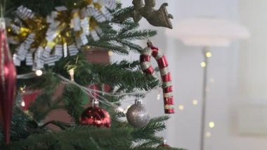 Noel ağacı dalının yavaş çekim şekerlemeleri ve arka planda bulanık parlak ışıklarla süslenmiş mücevherleri..