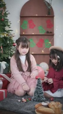 İki sevimli küçük kız süslü ve rahat oturma odasında sıcak Noel atmosferinin tadını çıkarıyorlar..