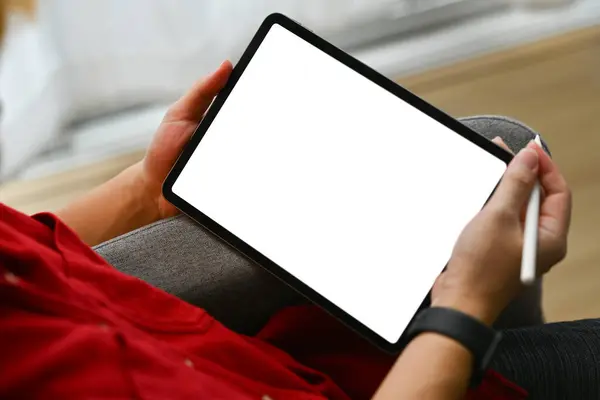 Close up shot young man hands holding digital tablet with blank screen sitting on couch at home.