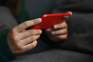 Kanepeye uzanıp akıllı telefondan sosyal medya videoları izleyen genç kadını kapatın..