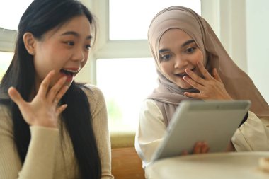 Kahve molasında cep telefonundan medya içeriğini izleyen iki heyecanlı genç bayan arkadaş..