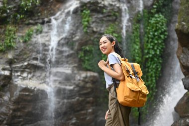 Sırt çantalı kadın turist portresi. Güzel tropikal şelale manzarasının tadını çıkarıyor..