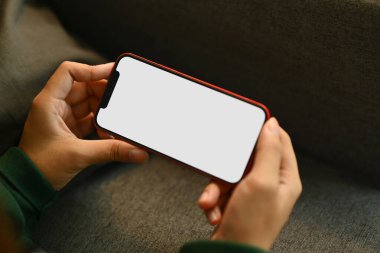 Kanepede uzanan, akıllı telefonuyla video izleyen ya da evde oyun oynayan genç bir kadın..