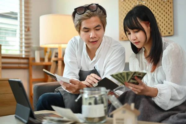 Young couple planning retirement finances or household expenses in living room.