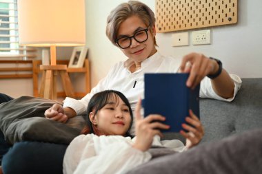 Oturma odasındaki kanepede birlikte oturup kitap okuyan genç çifte bayılıyoruz.. 