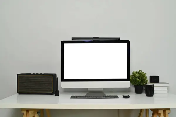 Modern workplace with bank screen of desktop computer on desk. White empty screen for graphic display montage.