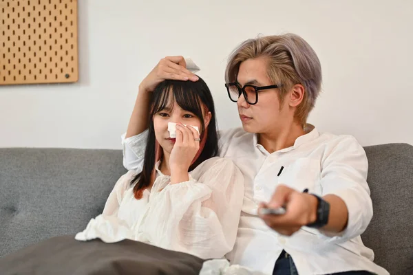 Young couple watching drama series on television in living room while spend weekend together.