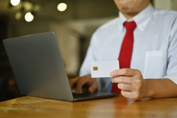 Businessman holding credit card using laptop doing online banking transaction or shopping in online store.