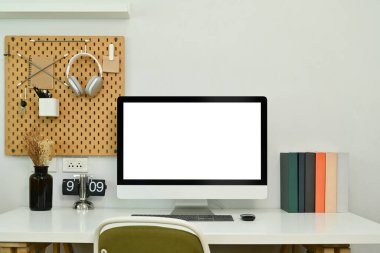 Boş bilgisayar monitörü, kitapları ve klasik çevirmeli saati olan yaratıcı iş yeri.