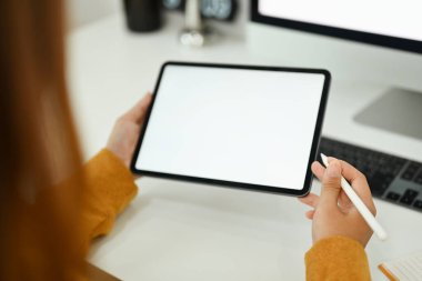 Modern iş yerinde dijital tablet kullanan genç yaratıcı kadını kapat.